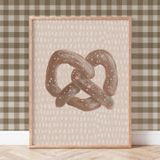 Framed artwork of a pretzel on a wall with a checkered pattern