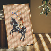 Framed artwork of a horse and cowgirl on a patterned background, placed indoors with natural light.