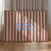 Striped artwork with 'COMME CI COMME CA' text in a wooden frame against a curtain backdrop.