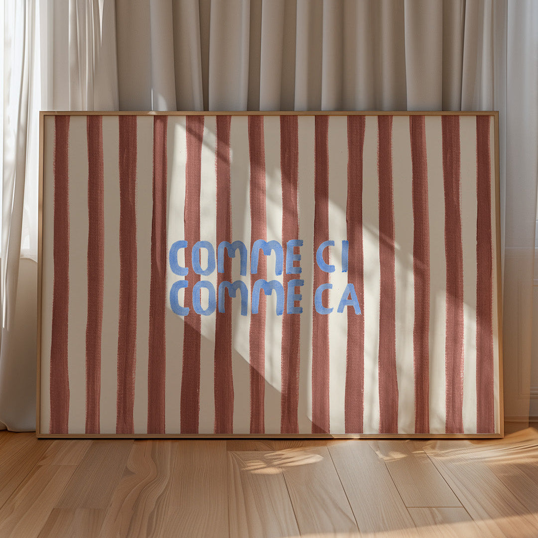 Striped artwork with 'COMME CI COMME CA' text in a wooden frame against a curtain backdrop.