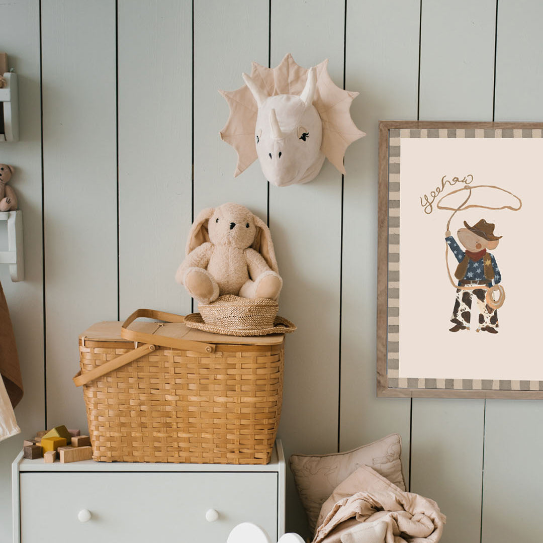 Children's room with toys, a basket, and a framed picture on a wooden wall.