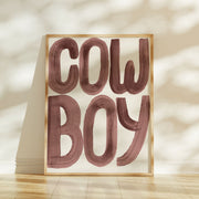 Framed artwork with 'COW BOY' text on a light background