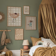 Children's bedroom with green walls, framed artwork, and a bed with brown bedding.