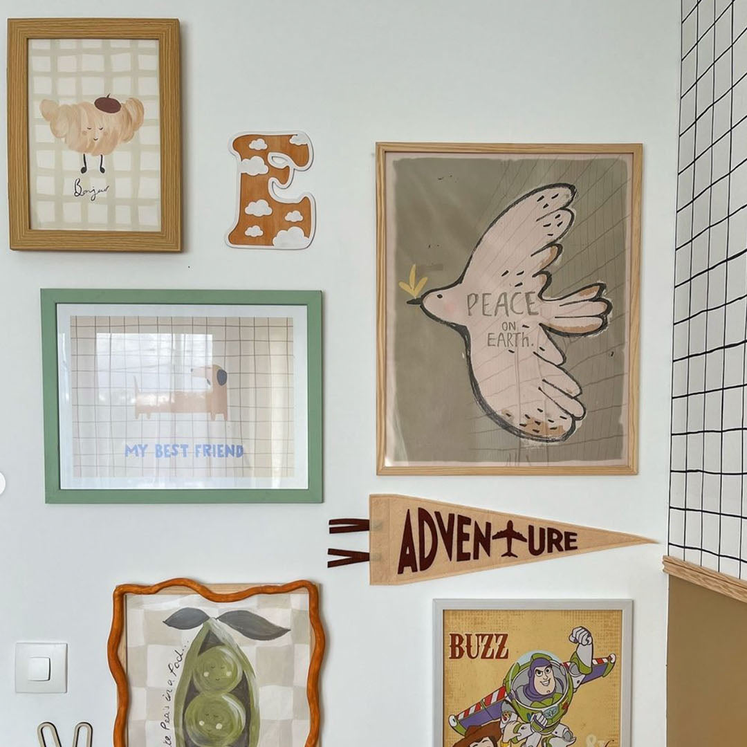 Wall with various framed pictures and decorations including a peace sign and cartoon characters.