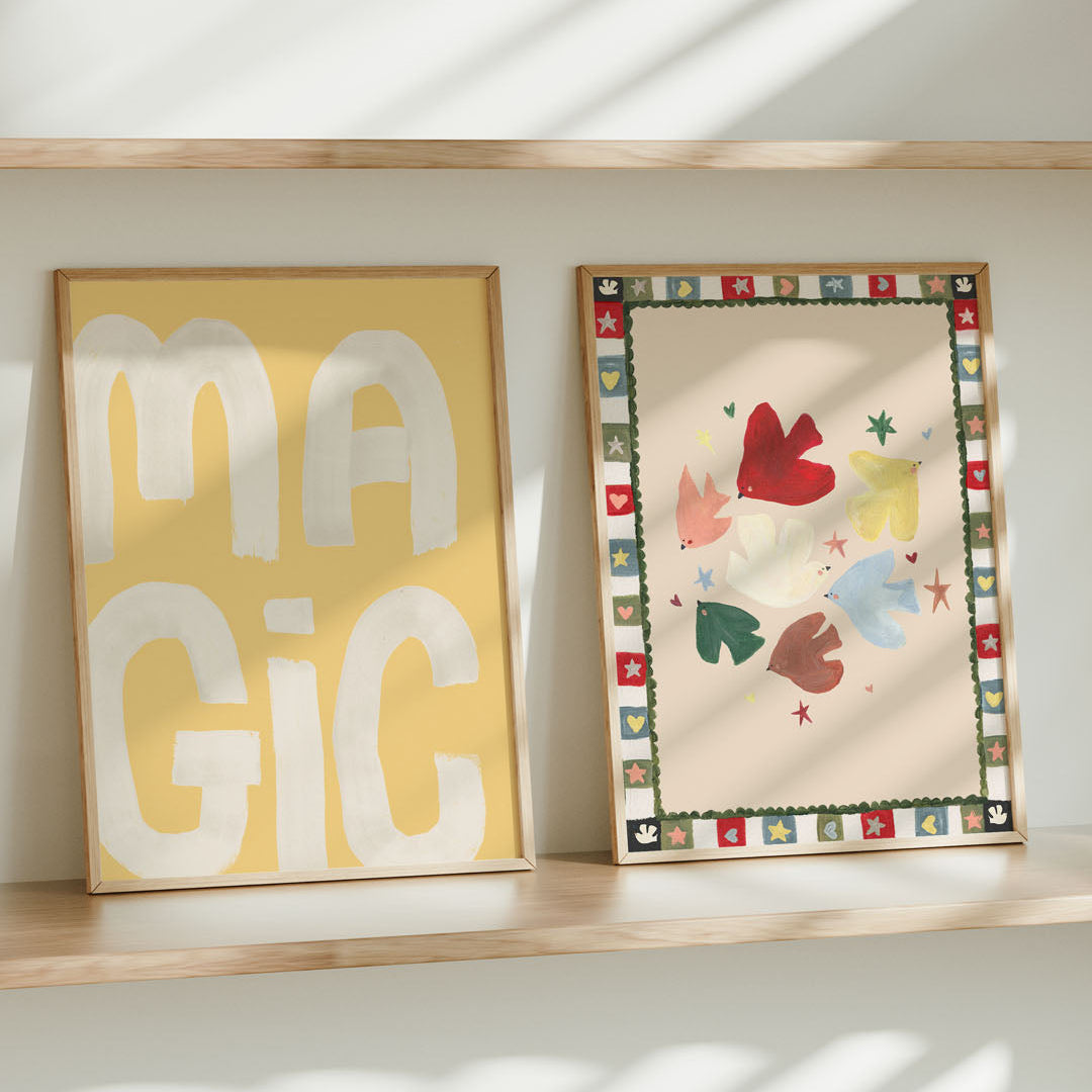 Two framed artworks on a shelf with 'MAGIC' on a yellow background and colorful abstract design.
