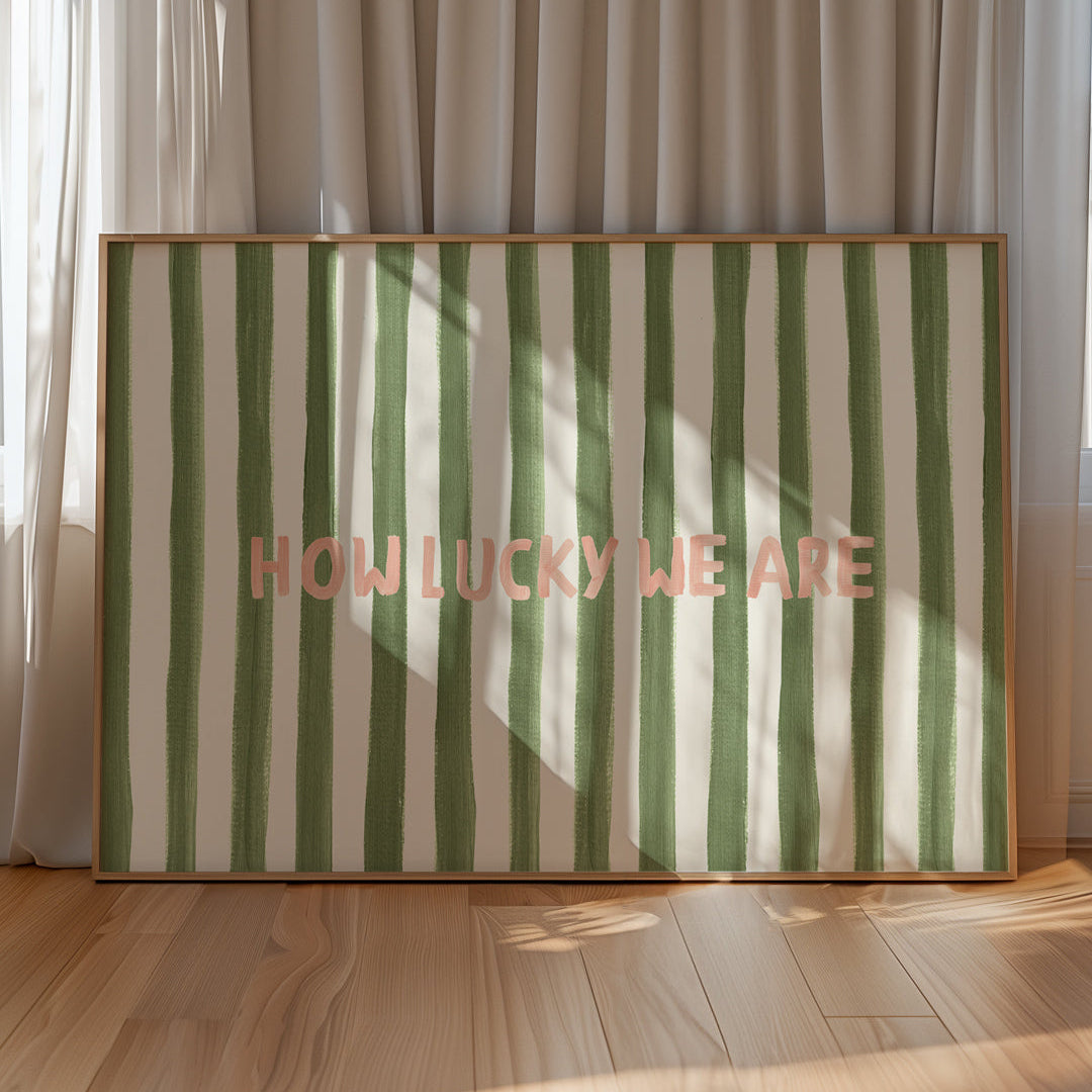 Striped wall art with 'HOW LUCKY WE ARE' text in a room with curtains and wooden floor.