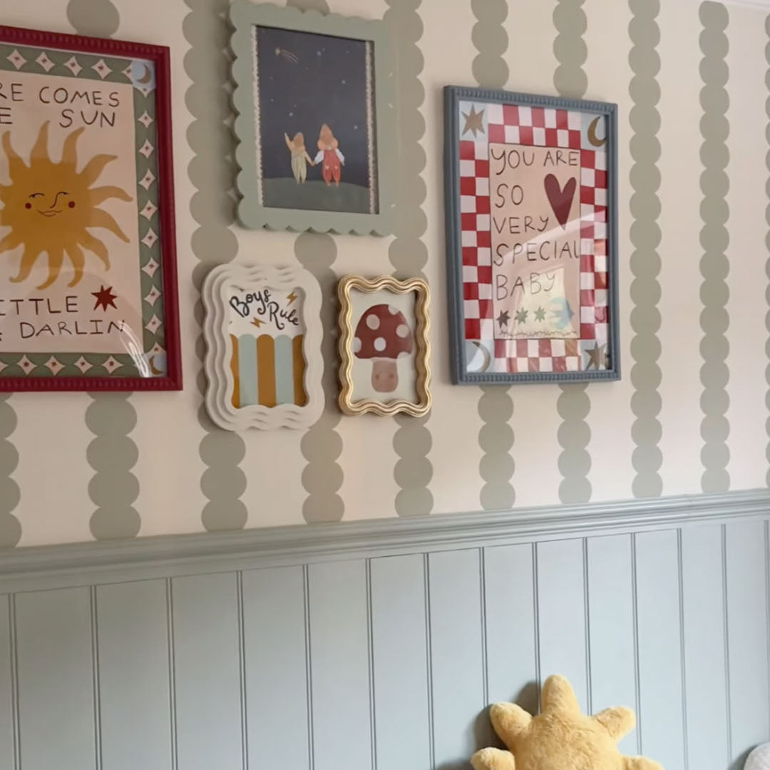 Nursery room with framed artwork and a sun-shaped plush toy.