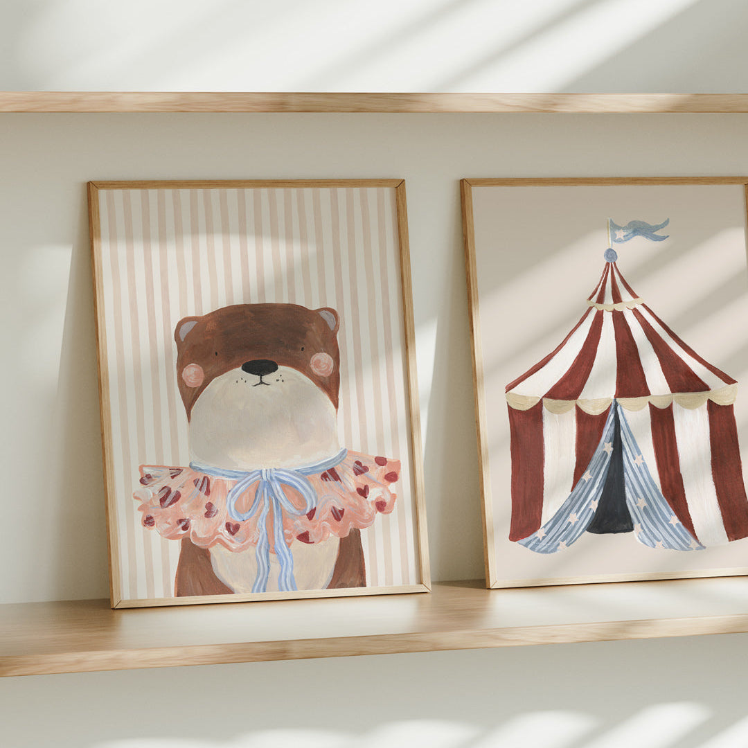 Two framed artworks on a shelf with an otter and circus tent design.