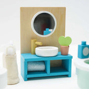 Miniature wooden dollhouse bathroom sink vanity set, featuring a blue cabinet, white bowl sink, gold faucet, round mirror on a natural wood panel, a heart-shaped potted plant, and a rolled towel.