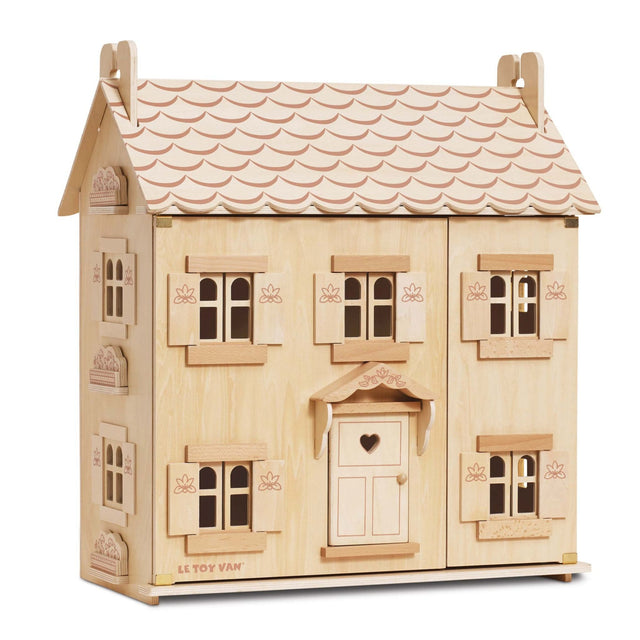 A wooden dollhouse with a light natural wood finish, featuring a scalloped pink roof, multiple windows with shutters, and a central door with a heart-shaped window. The brand name 'EL.