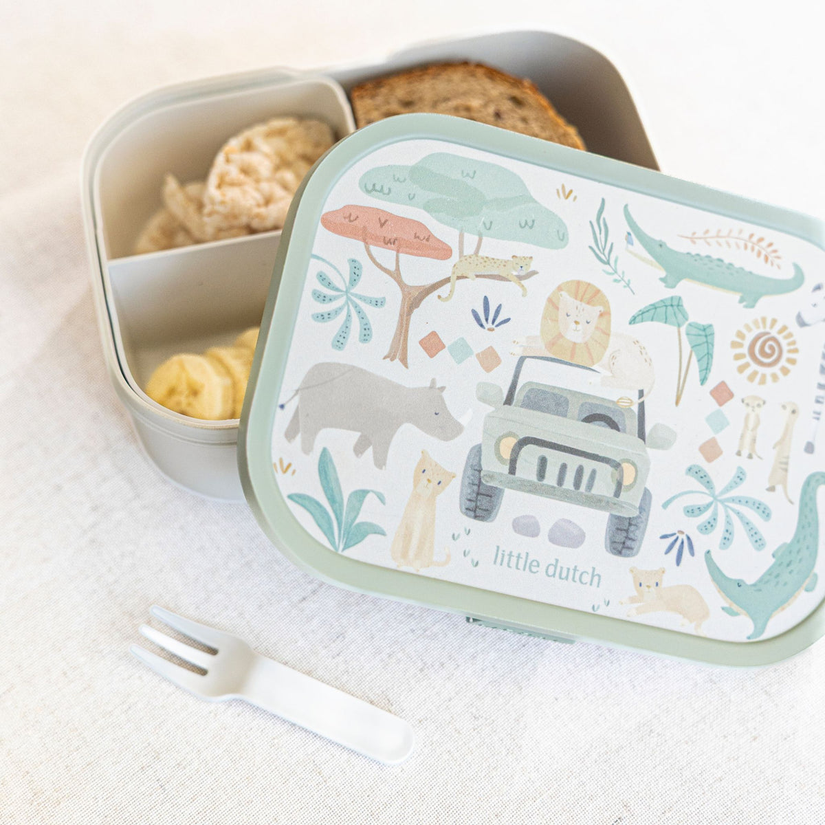A Little Dutch children's lunch box with a decorated lid featuring safari animal illustrations and the text 'little dutch', shown next to an open compartment box with snacks.