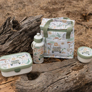 Little Dutch coordinated picnic-style lunch set arranged on a log outdoors, including a lunchbox, water bottle, lunch bag, and small container. The items have a safari-themed print with animals and vehicles in muted green, beige, brown, and white tones.