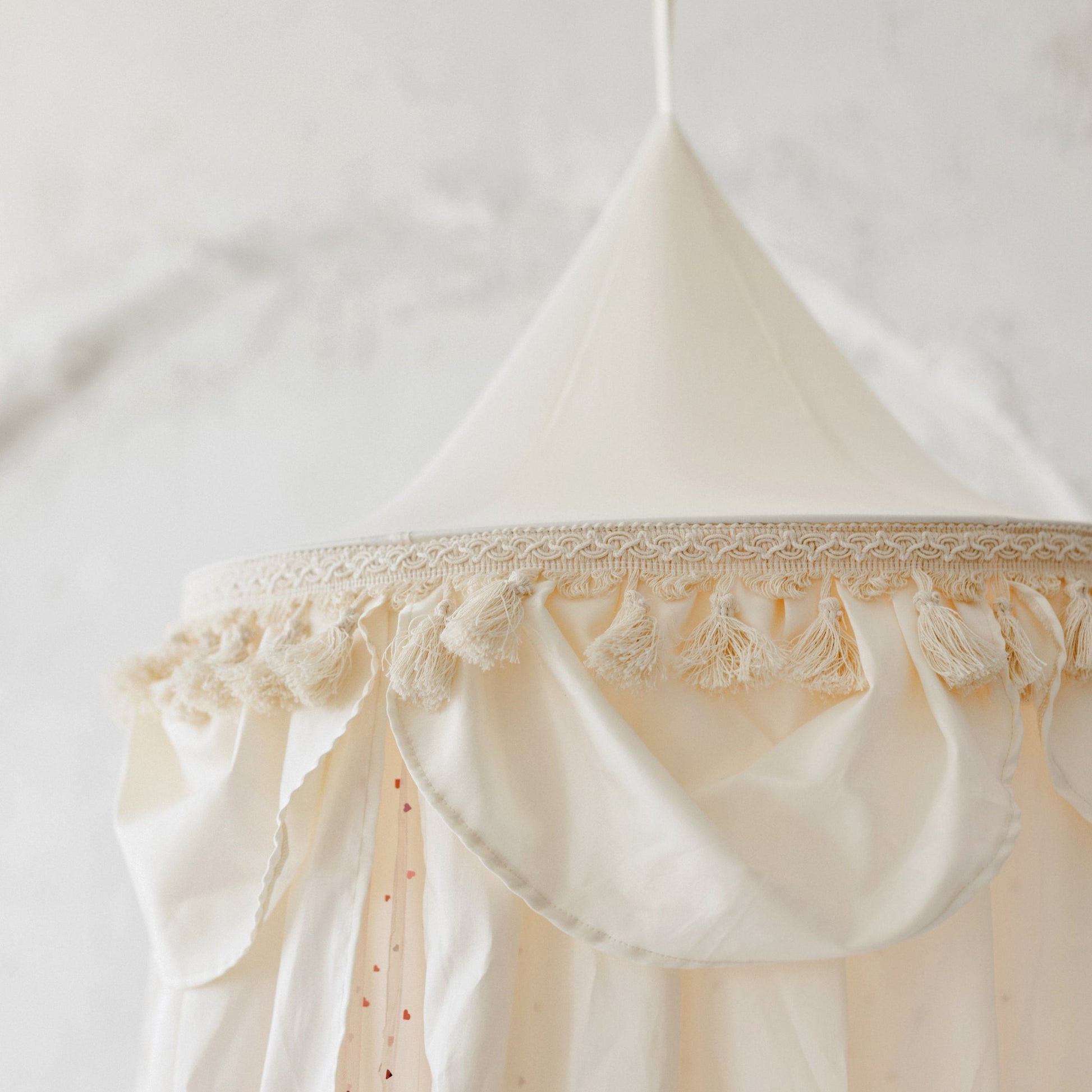Cream-coloured hanging canopy with tassels and trim