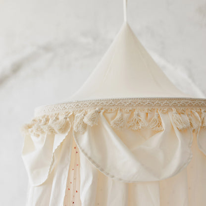 Cream-coloured hanging canopy with tassels and trim