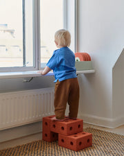 Child standing on MODU blocks by a window