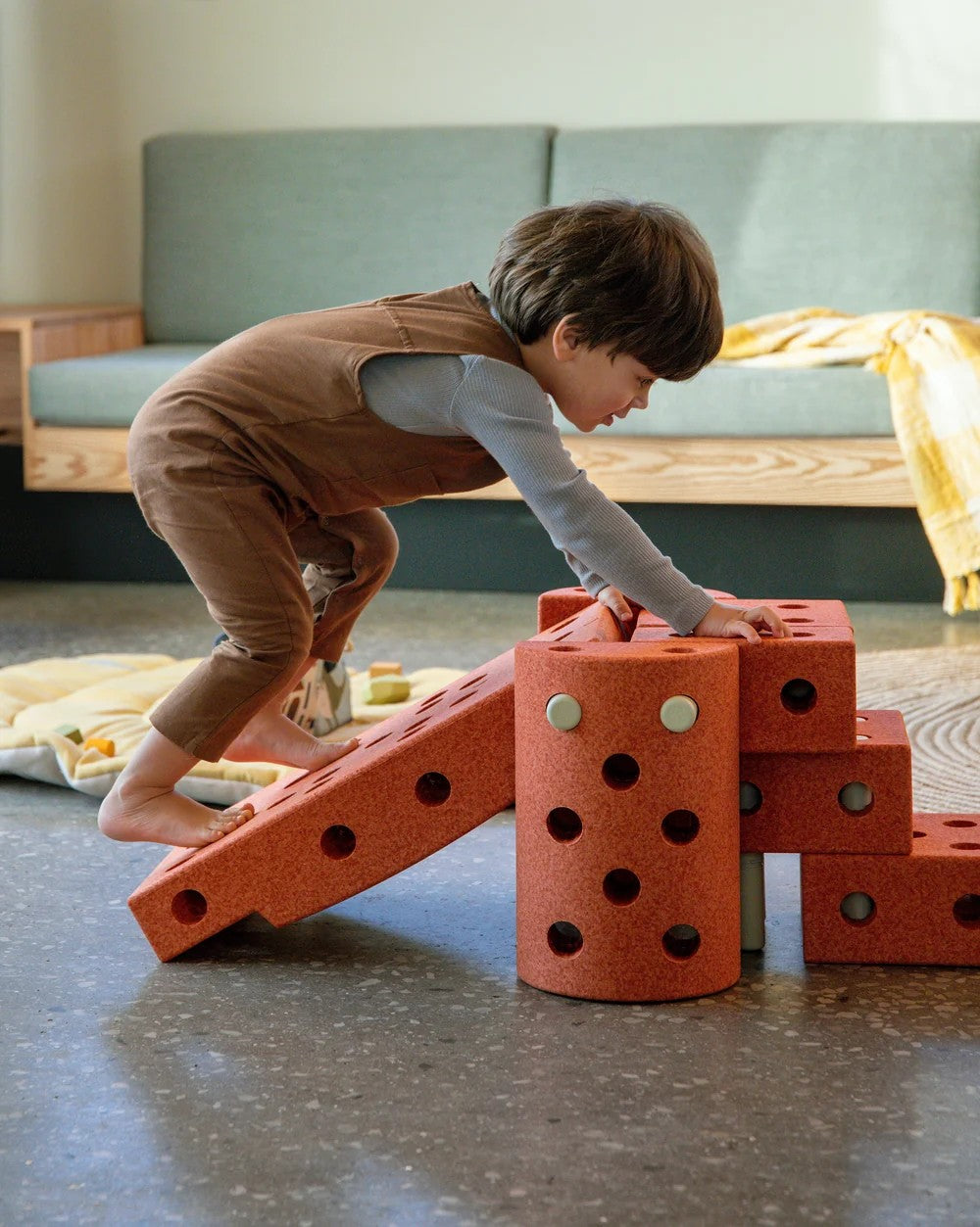 Child playing with red building blocks on a concrete floor.