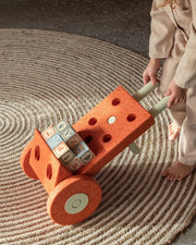 Child playing with a toy cart on a textured floor