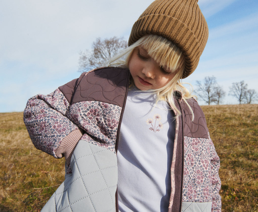 Blonde girl in a hat and Wheat jacket looking down