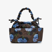 A structured drawstring handbag with a dark brown base and a blue rose floral print, featuring a matching elasticated top handle, photographed on a clean white background.