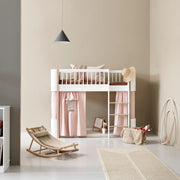 Oliver Furniture Wood Mini+ Low Loft Bed in white and oak with pink curtains and play space underneath in a modern Scandinavian-style children's bedroom.