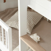 Close-up of an Oliver Furniture Wood Mini+ Low Bunk Bed featuring a white and oak frame, designed for comfort and small spaces, ideal for siblings sharing a room. 