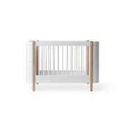 Oliver Furniture Wood Mini+ Cot Bed in white and oak with convertible junior bed kit, designed for infants to 9-year-olds with adjustable mattress heights and removable bars.