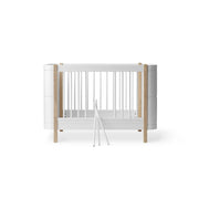 Oliver Furniture Wood Mini+ Cot Bed with Junior Kit in white and oak, a convertible 0-9 year sleeping solution with adjustable cot base, removable bars, and junior bed conversion kit included.