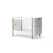 Oliver Furniture Wood Mini+ Cot Bed with Junior Kit in white and oak, a convertible baby bed for ages 0-9 years featuring adjustable mattress height, removable bars, and transformation into a junior bed or daybed.