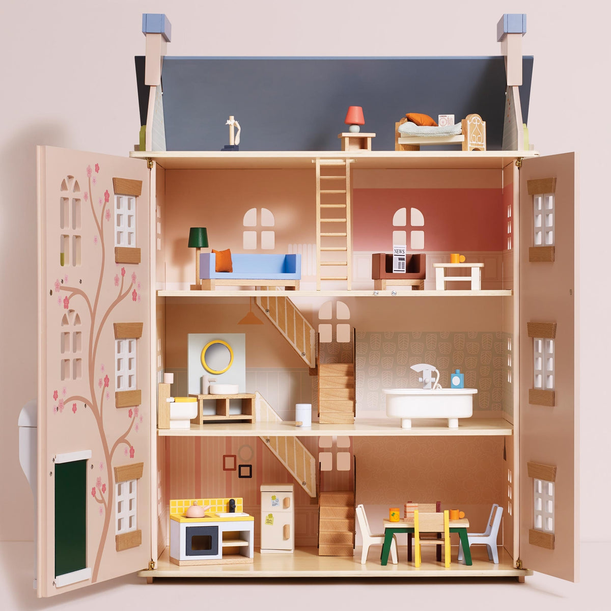 A miniature dollhouse with open doors, showing multiple interior floors with furniture, stairs, a kitchen, bathroom, and a small roof top, photographed against a plain light beige background.