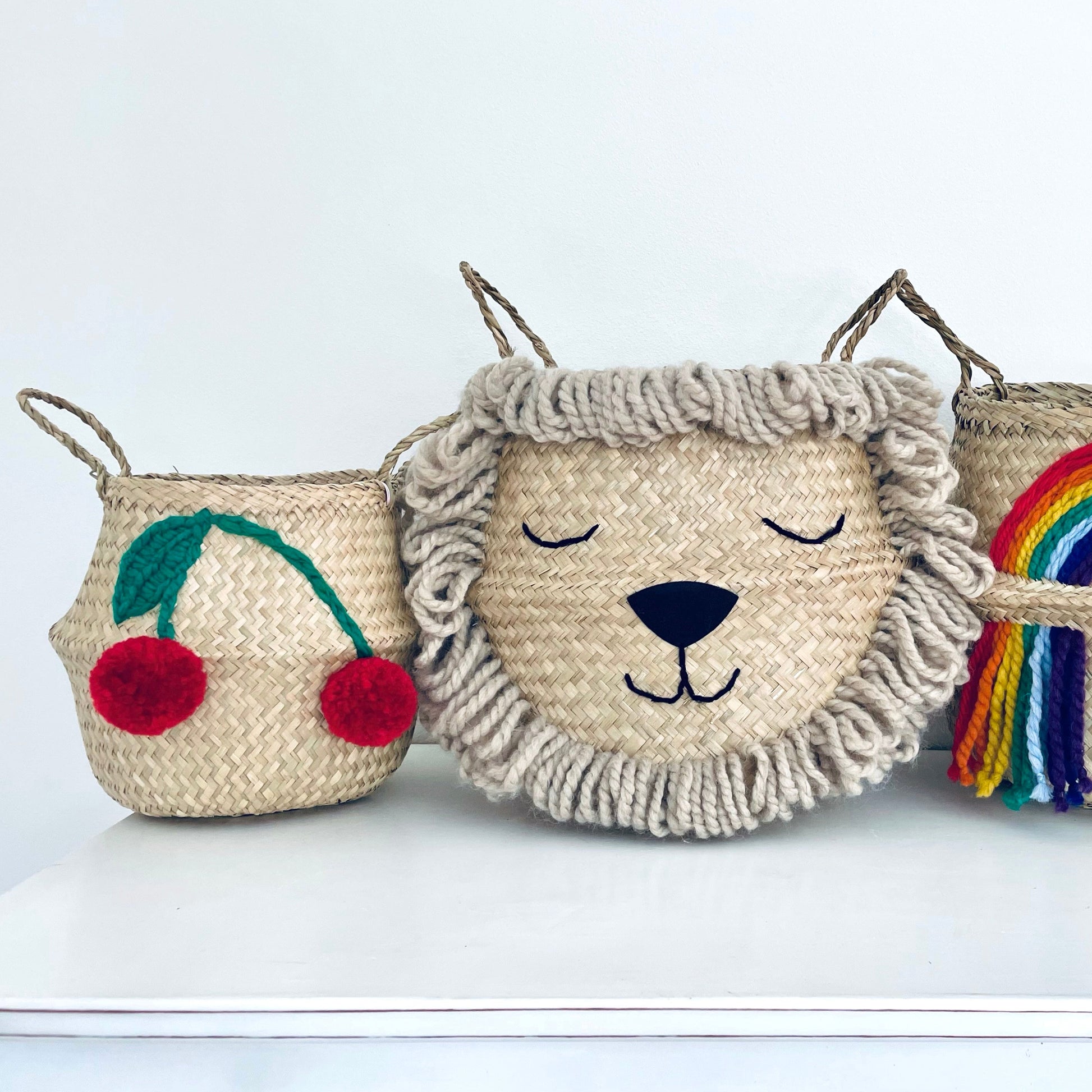 Three woven baskets with decorative elements on a white background