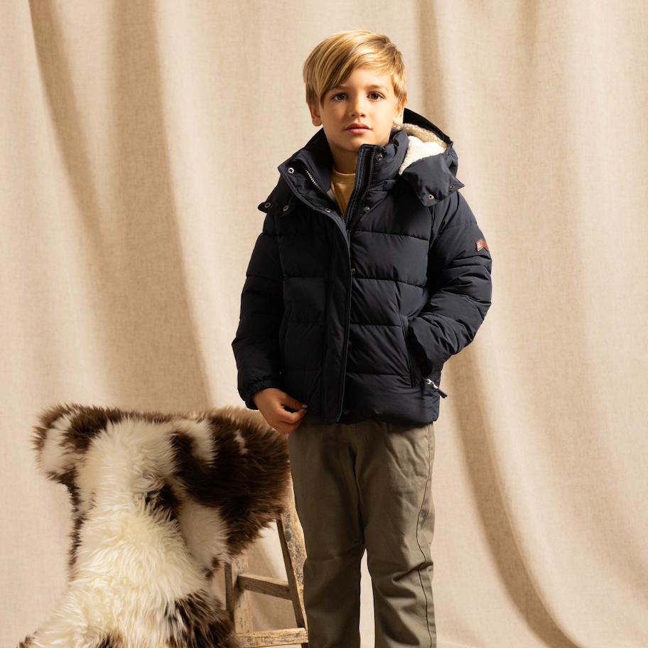 Boy in a studio wearing a navy blue puffer jacket