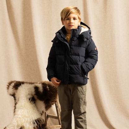 Boy in a studio wearing a navy blue puffer jacket
