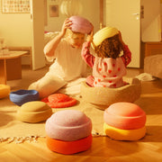 A woman and a child sit on a wooden floor in a warm, sunlit room, playing with Stapelstein Stepping Stone Winter Special. 