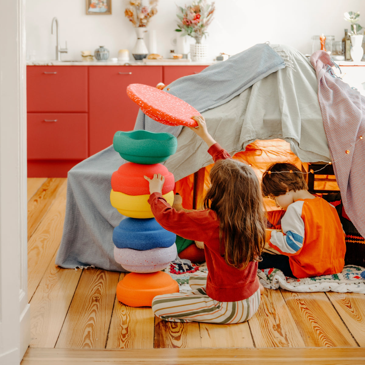 Two children playing in a cosy indoor play scene with Stapelstein Stepping Stones 6+1 Set Winter Special.