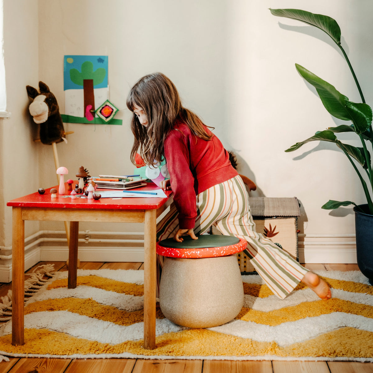 A child in a red top and striped trousers sits on a Stapelstein dynamic winter special set.