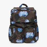 A Tiba + Marl dark brown backpack featuring a blue rose floral print over a subtle camouflage pattern, with multiple zippered compartments and a top handle, shown against a plain white background.