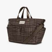 A brown and beige plaid diaper bag with dark brown handles and a matching shoulder strap, shown on a clean white background.