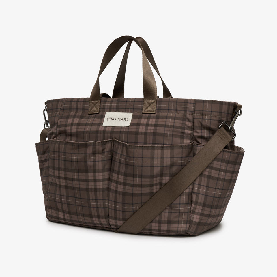 A brown and beige plaid diaper bag with dark brown handles and a matching shoulder strap, shown on a clean white background.