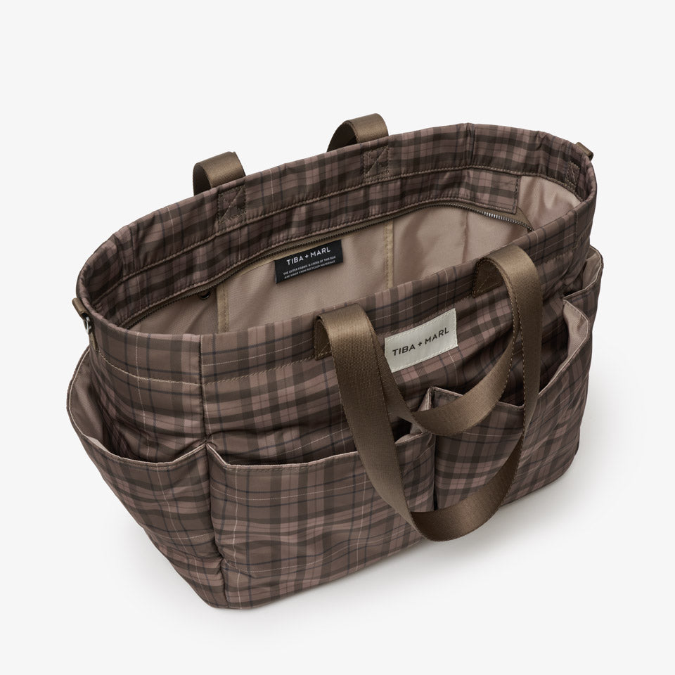 A brown and beige plaid tote bag with dark brown handles, shown from an elevated angle on a light gray background.