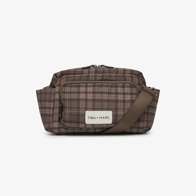 A brown and beige plaid crossbody bag with a brown strap and a white brand label reading 'TBA + MARI', shown against a plain white background.