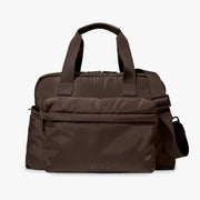 A dark brown nylon duffel bag with top handles, a front zippered pocket, and an adjustable shoulder strap, shown against a plain light gray background.