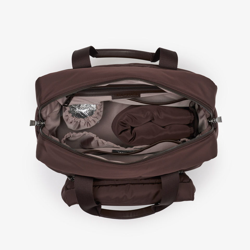 A dark brown duffel bag shown from a top-down view, open to reveal its interior storage compartments and packed items, set against a plain white background.