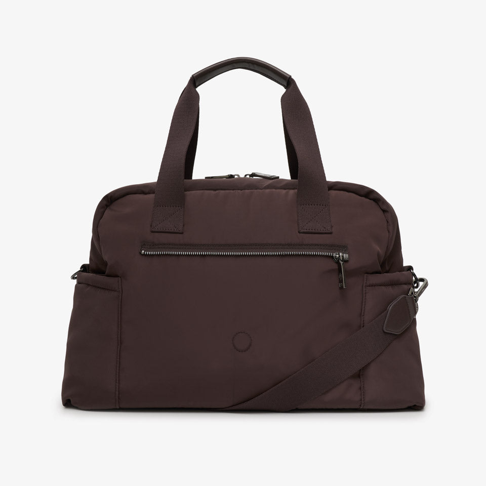 A dark brown nylon duffel bag with dual top handles, a front zippered pocket, and an adjustable shoulder strap, shown against a plain light gray background.