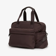 A dark brown nylon duffel bag with dual top handles, a front zippered pocket, and a side strap attachment, shown on a light gray background.
