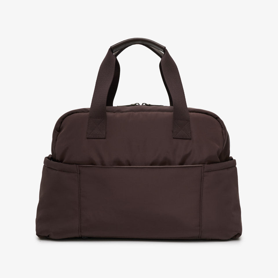 A dark brown nylon duffel bag with two top handles and a front slip pocket, shown against a plain white background.