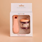 Tiny Harrow Chocolate Pudding gift set in its original white packaging, featuring a peach-colored chocolate spoon and a small jar of chocolate pudding with a peach lid, set against a solid beige background.
