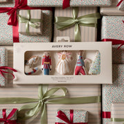 Avery Row Christmas Tree Decorations Set of 5 in its original window box packaging, surrounded by wrapped Christmas gifts with red ribbons and green satin bows.