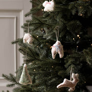 Handmade Christmas ornaments hanging on a decorated Christmas tree, including a tree-shaped ornament, a polar bear, a reindeer, a pair of owls, and a hedgehog with warm string lights in the background.