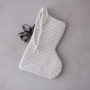 White crocheted Christmas stocking on a grey background