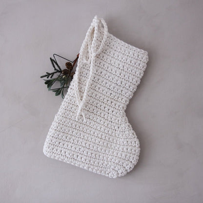 White crocheted Christmas stocking on a grey background
